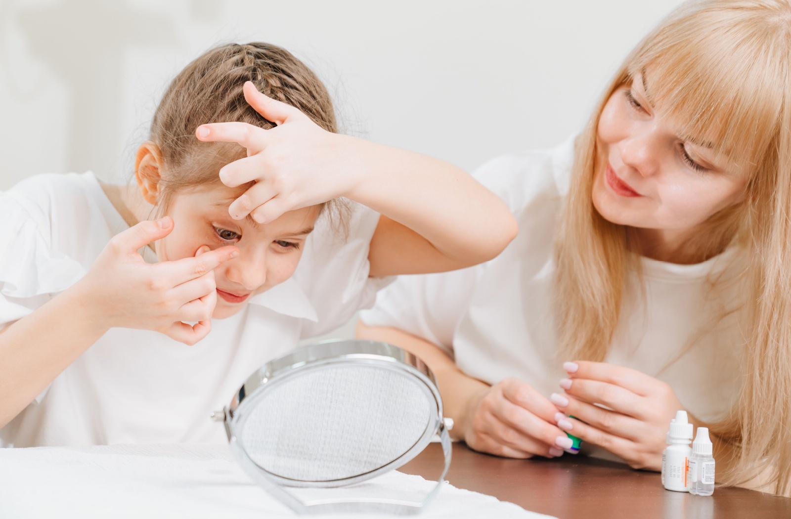 An eye doctor helps their young patient practice putting in their daily contact lenses.
