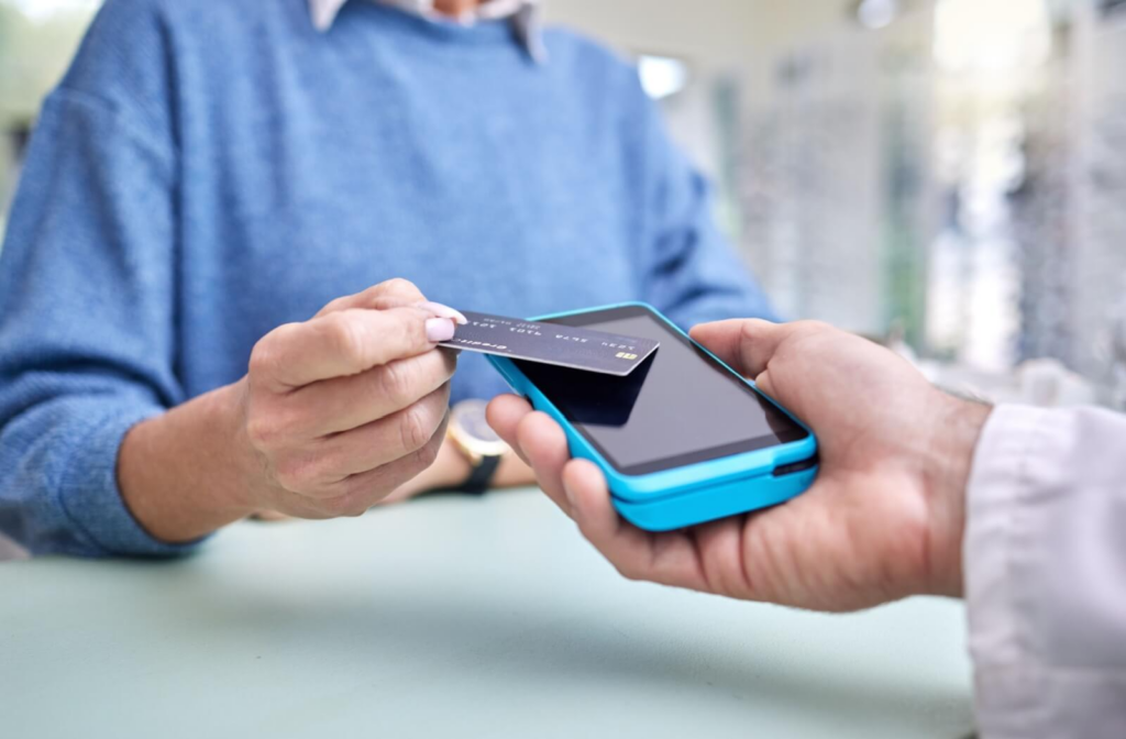 A close-up image of an older adult paying for the portion of their eye exam that wasn't covered by their health insurance.